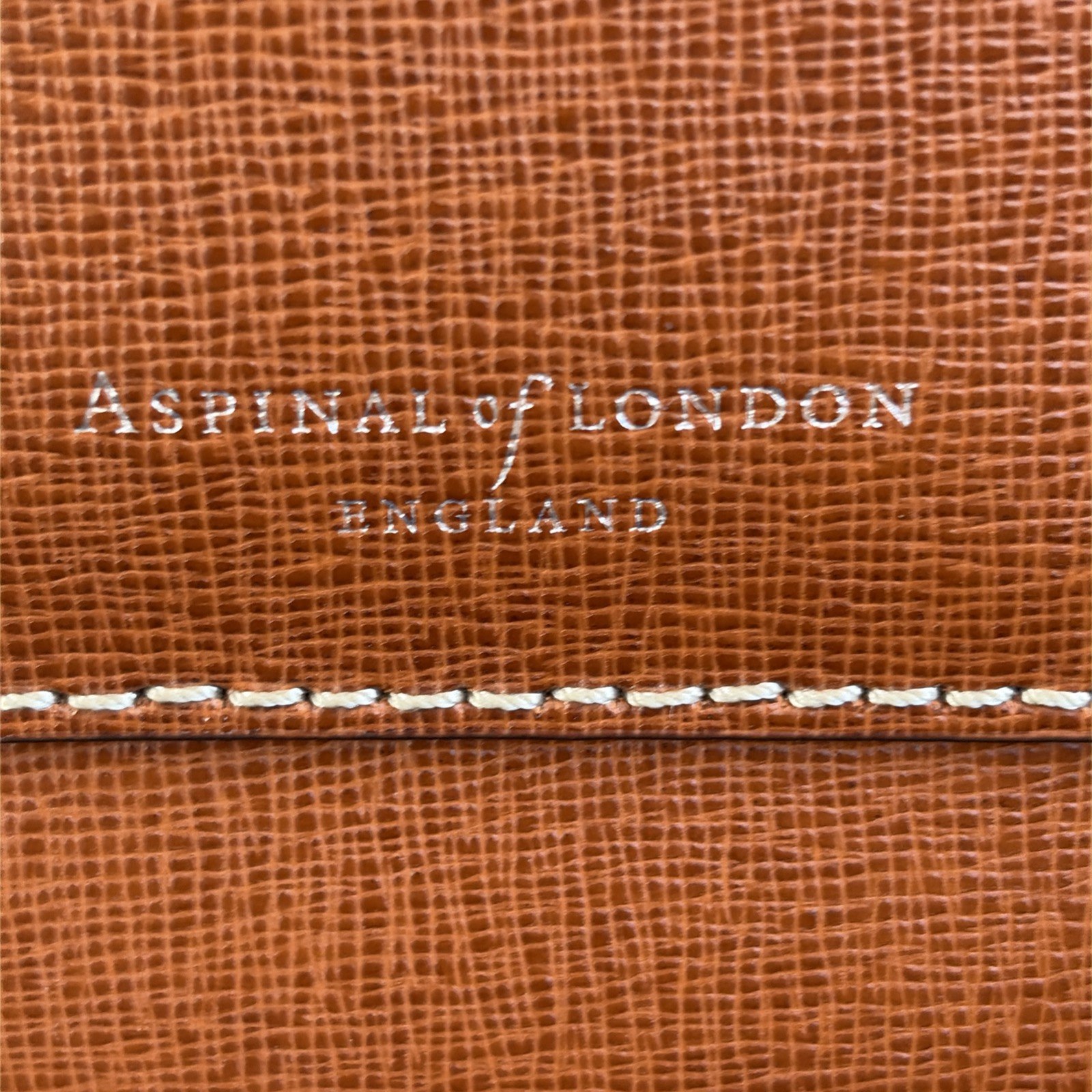 Aspinal of London England logo debossed into the tan saffiano leather of the Reporter North South bag