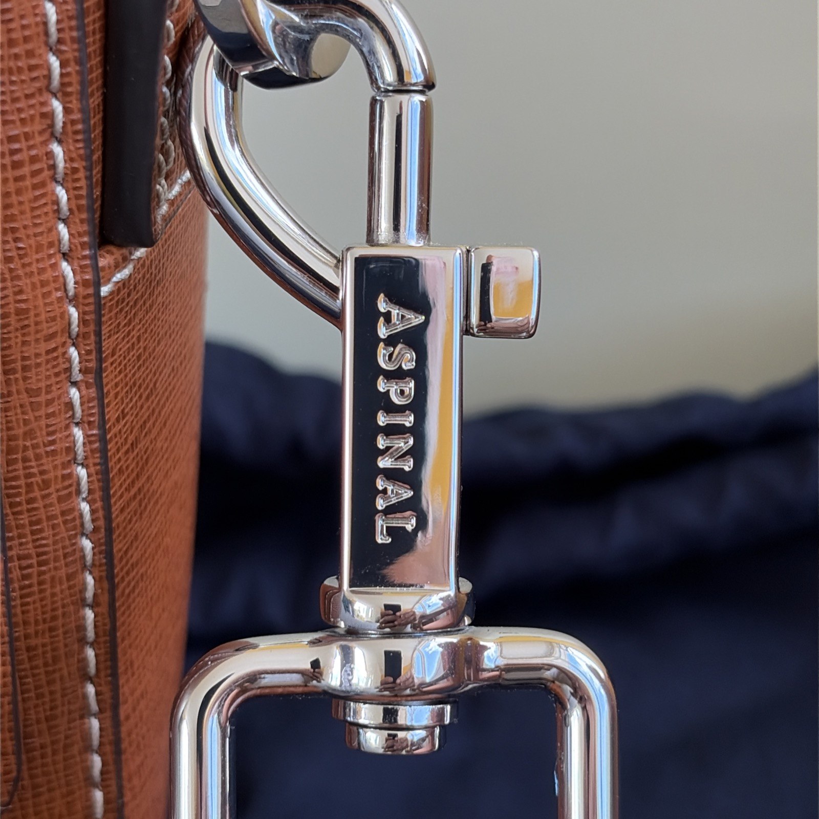 Close-up of the silver-toned swivel clip and Aspinal branding on the Reporter North South crossbody strap
