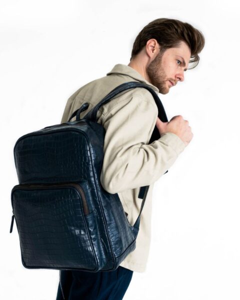 Man wearing a stylish leather backpack in a studio setting