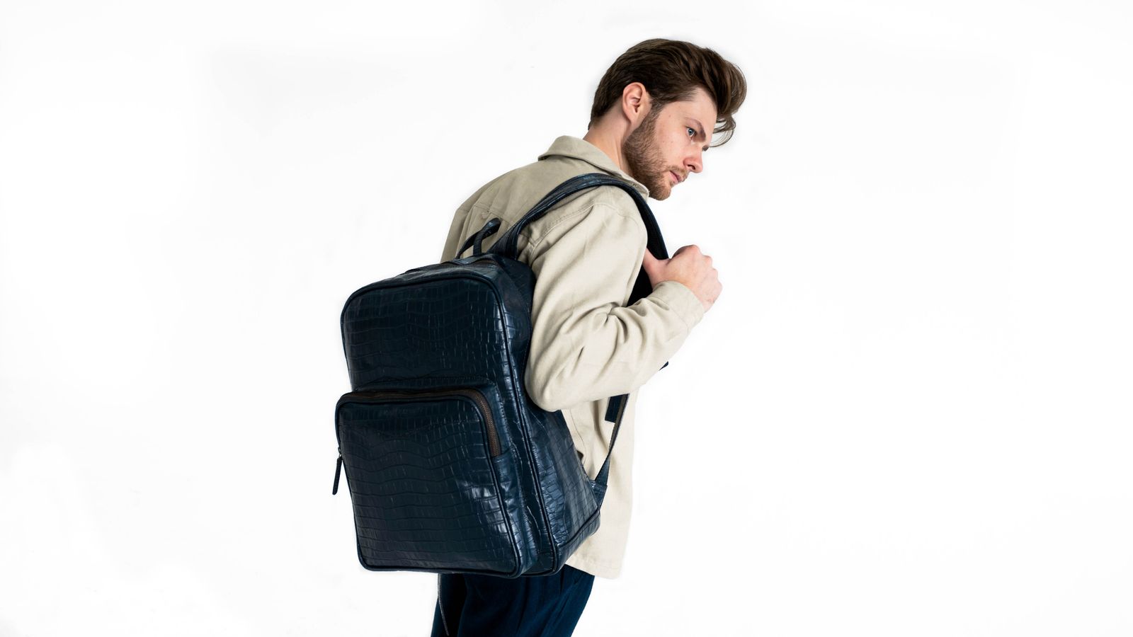 Man wearing a stylish leather backpack in a studio setting