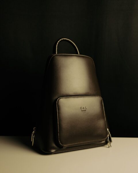 Sleek black leather backpack on a moody studio background