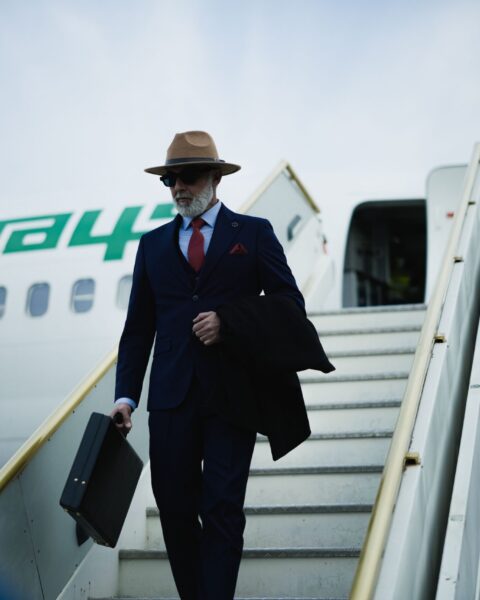 Stylish businessman carrying a black briefcase while descending aircraft stairs