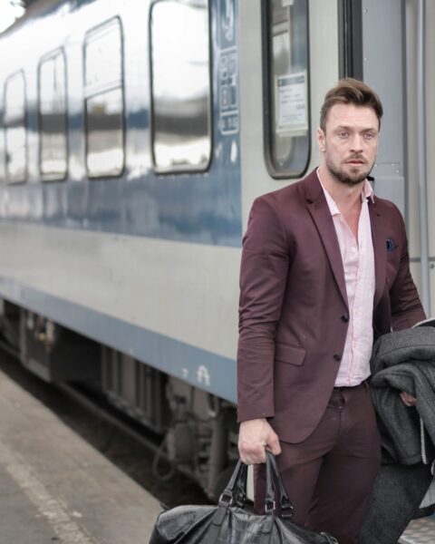 Man in a suit exiting a train platform, carrying a black leather holdall bag
