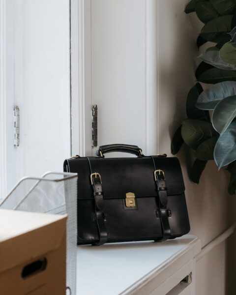 Black leather briefcase on a desk in a minimalist office setting