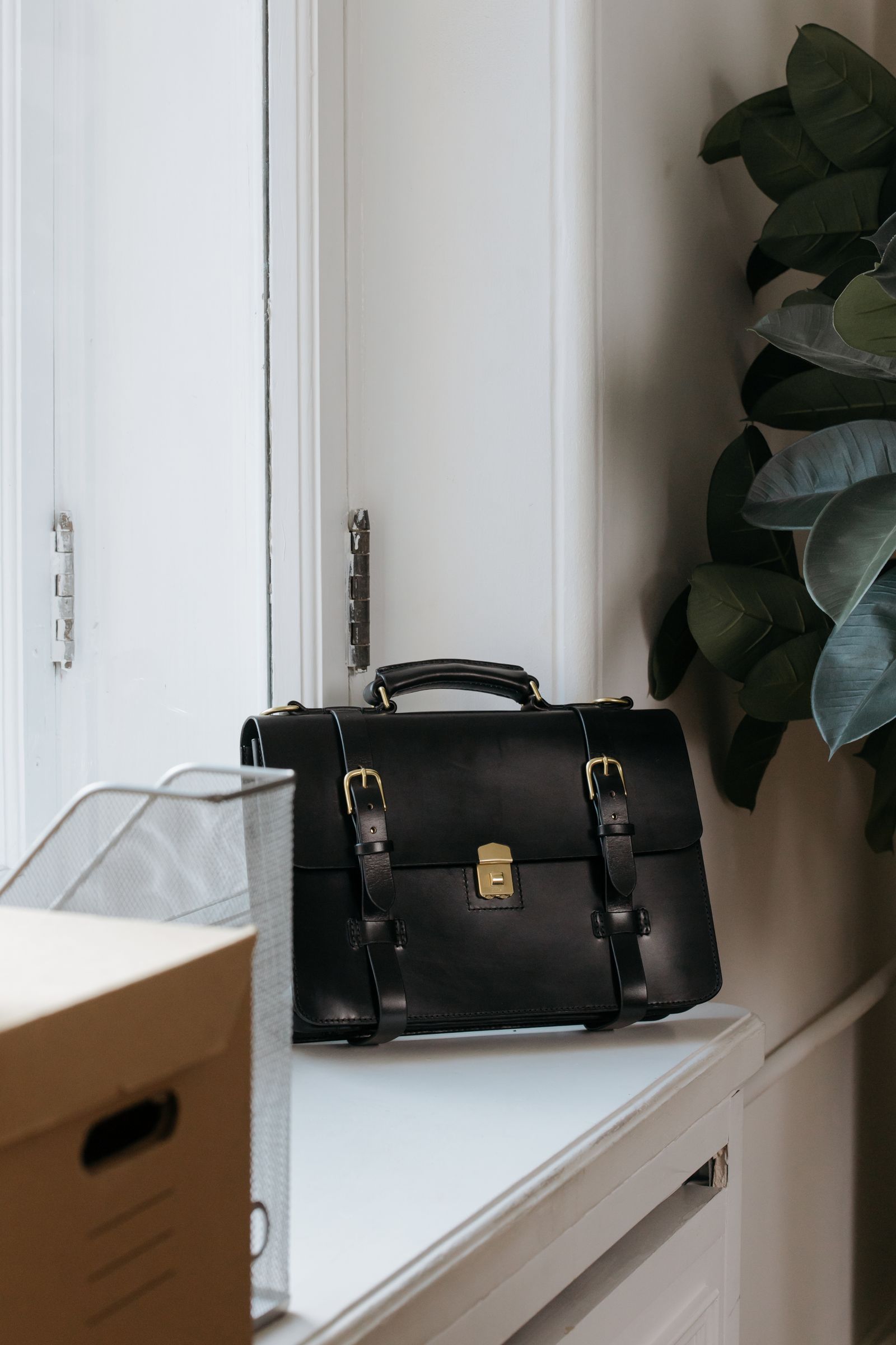 Black leather briefcase on a desk in a minimalist office setting