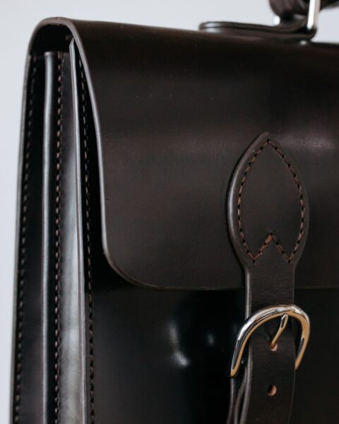 Close-up of a brown leather briefcase showing stitching and hardware detail