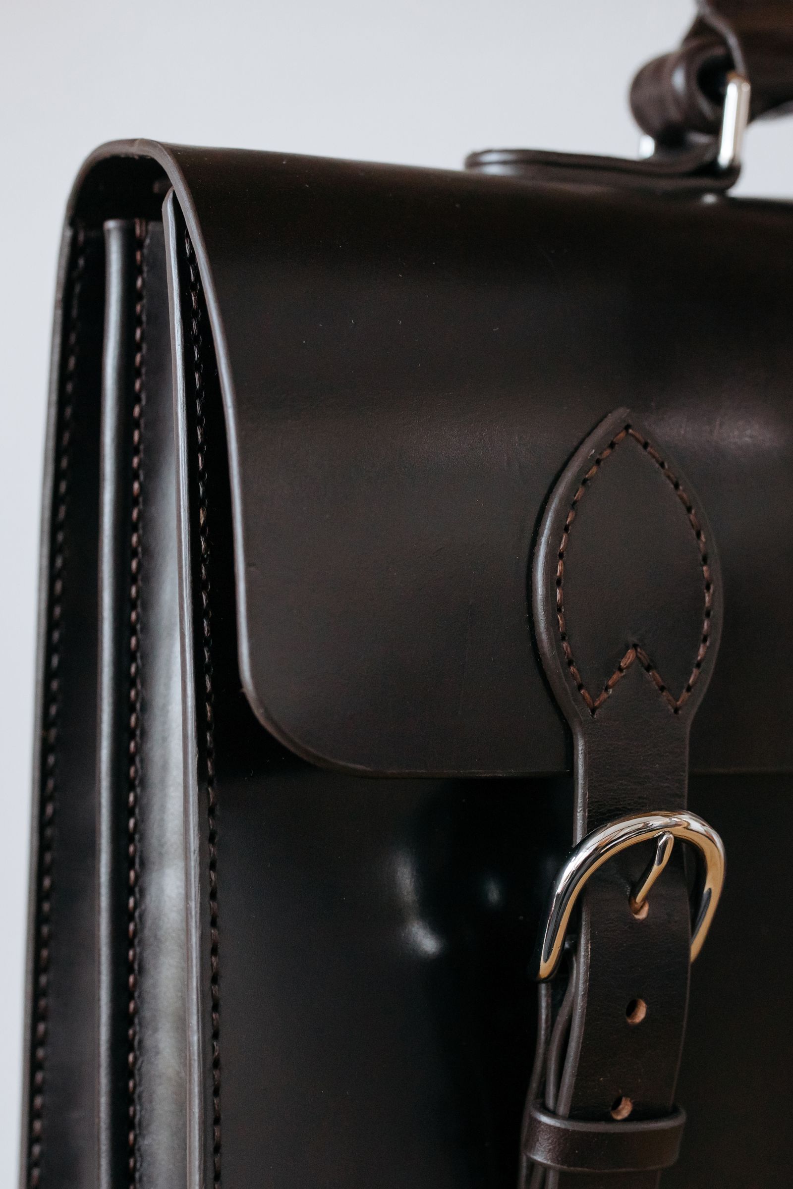 Close-up of a brown leather briefcase showing stitching and hardware detail