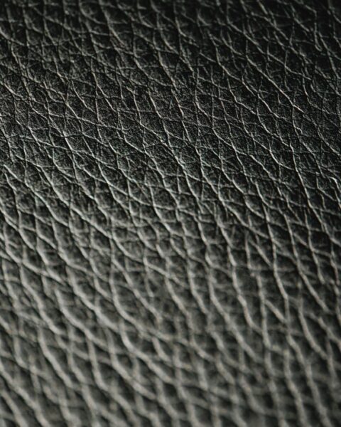 Close-up macro shot of black leather showing a cross-hatch, diamond-textured pattern pressed into the surface