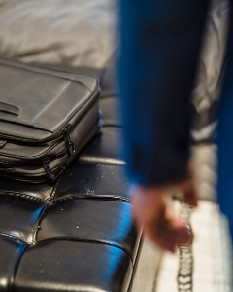 Black leather briefcase resting on a leather ottoman in a minimalist interior