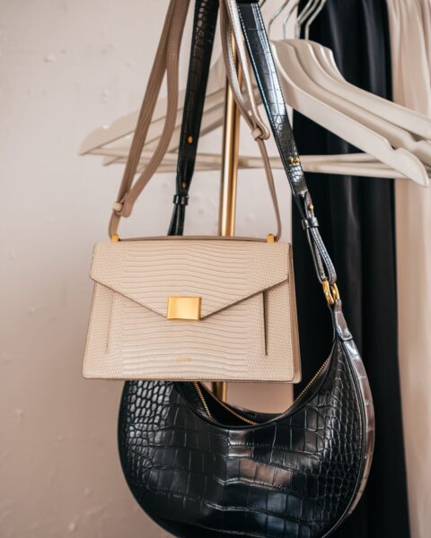 Leather handbags hanging on a clothing rack in a boutique, illustrating a designer sample sale