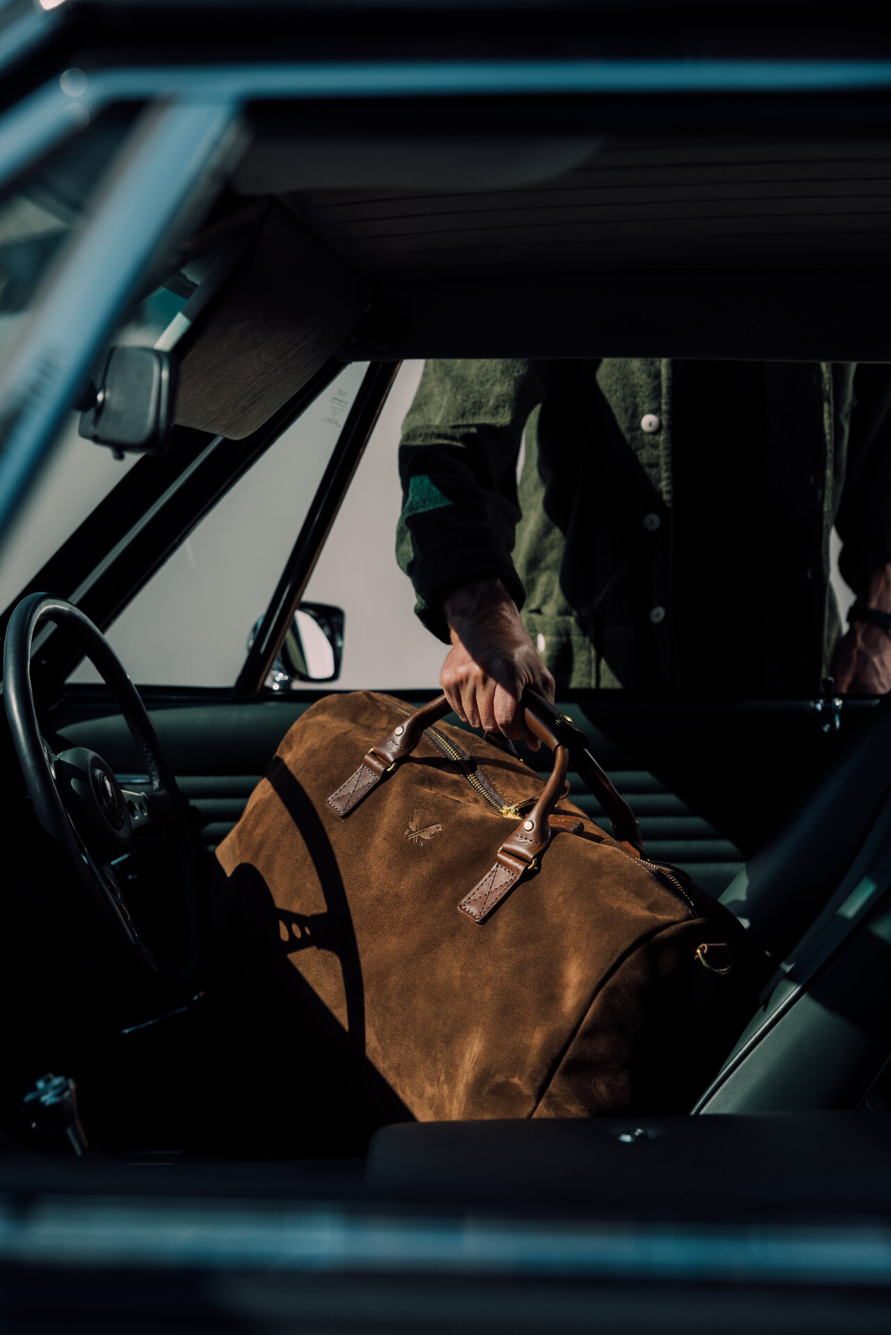 Close detail of the Bennett Winch Suede Commuter's leather handles and brass hardware