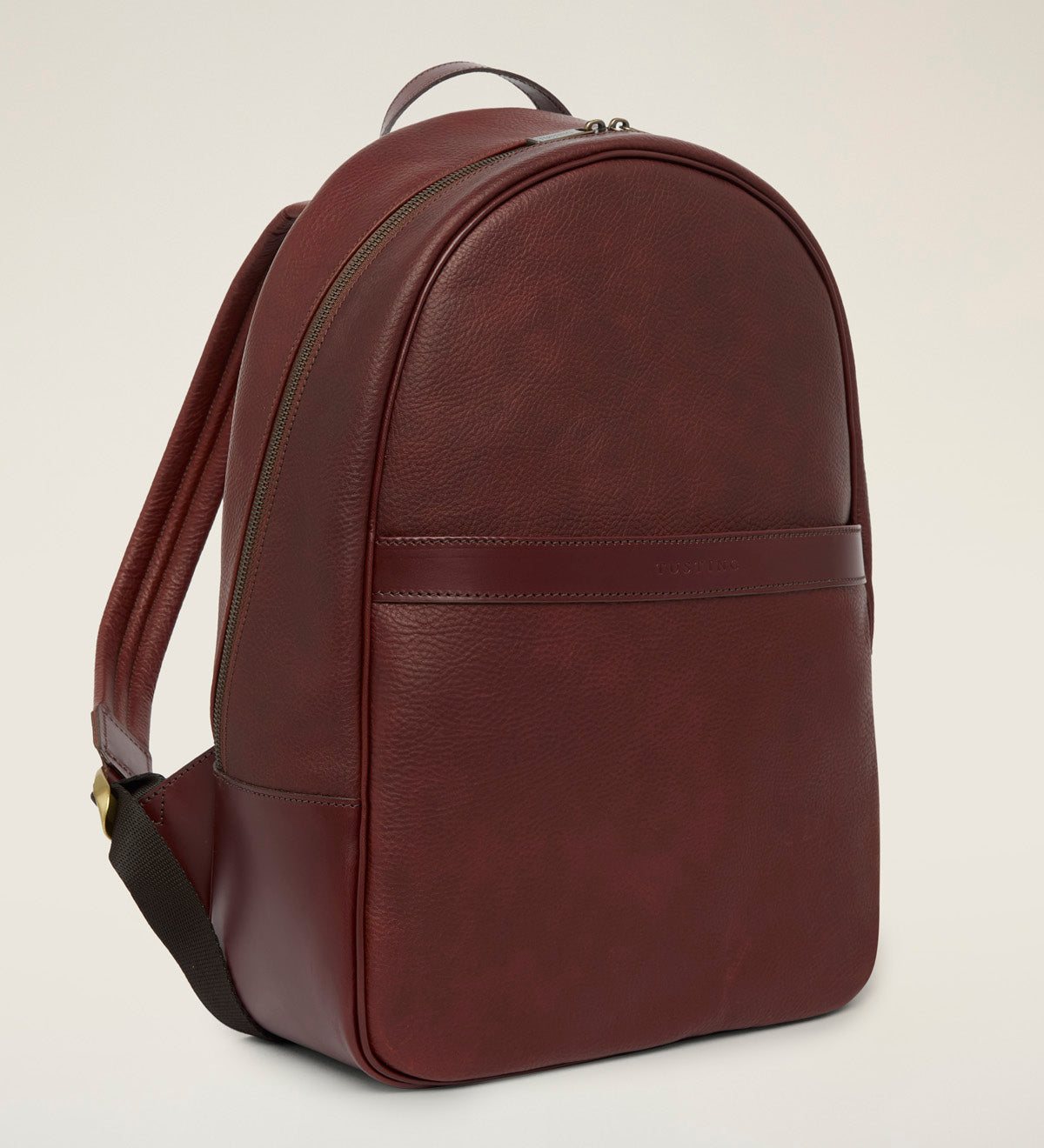 Tusting Millbrook leather backpack in Chestnut Elba, three-quarter side view showing the padded shoulder strap and front pocket