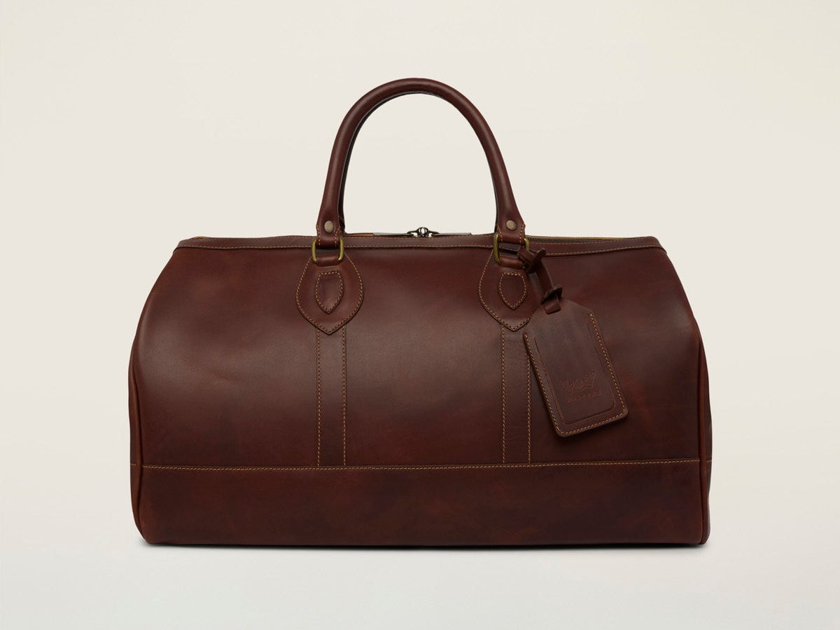 Tusting Weekender holdall (Small) in Sundance leather, front view with rolled top handles and a leather luggage tag